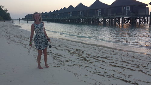 Portrait of woman standing on beach against sky