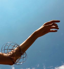 Low angle view of hand against blue sky