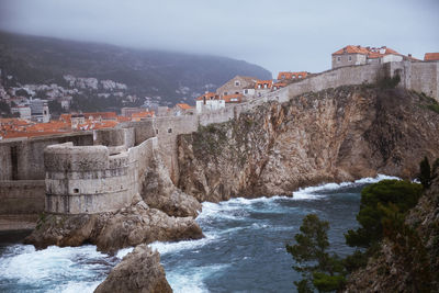 Buildings by sea against sky