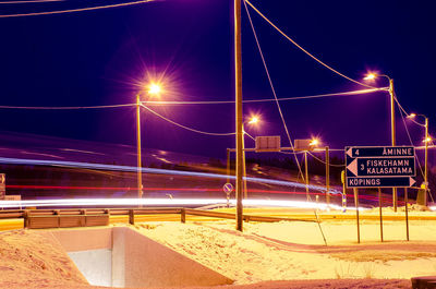 Light trails on road against sky at night