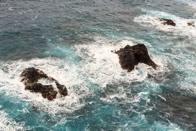 High angle view of wave splashing on rock