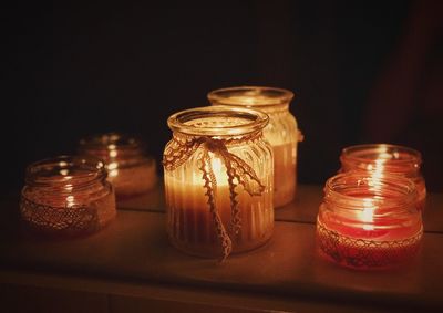 Lit candles in container on table against black background