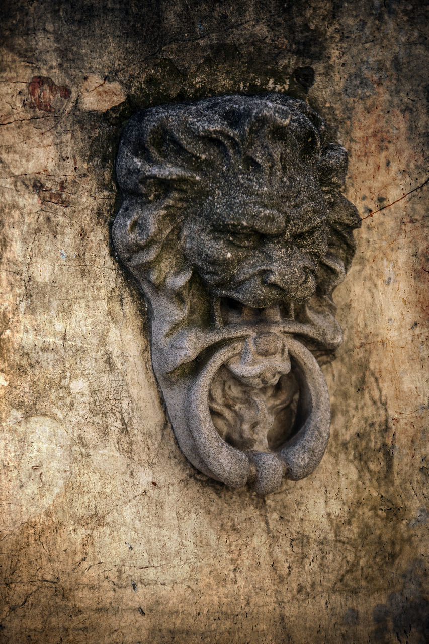 CLOSE-UP OF OLD STATUE AGAINST WALL