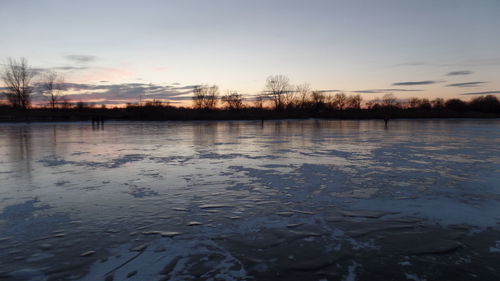 Scenic view of river against sky at sunset