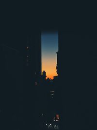 Silhouette buildings against clear sky at night