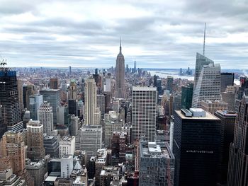 Aerial view of buildings in city against cloudy sky