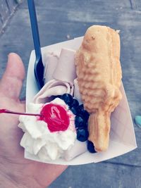 Close-up of hand holding ice cream cone on table