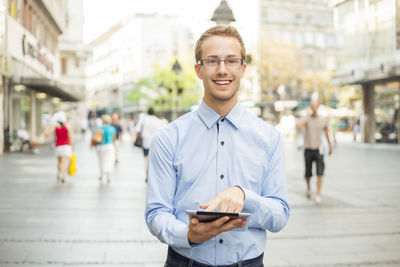 Portrait of smiling young man standing in city