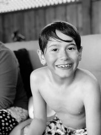 Portrait of shirtless wet smiling boy sitting outdoors