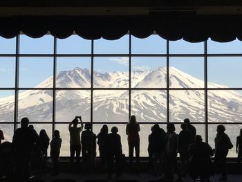 Silhouette people in city against sky seen through window