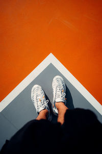 Low section of person standing against orange wall