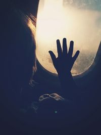 Close-up of silhouette hand against sunset sky