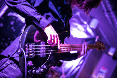 Midsection of man playing bass guitar