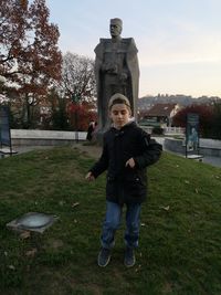 Full length of boy standing by tree against sky