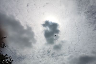 Low angle view of sunlight streaming through clouds