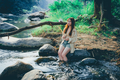 Woman sitting on rock in forest