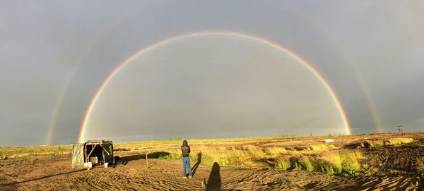 Scenic view of field against rainbow in sky