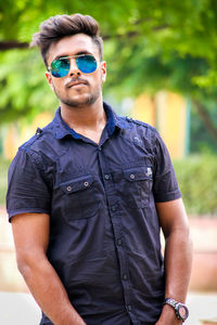 Portrait of young man wearing sunglasses while standing outdoors