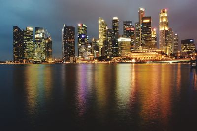 River by illuminated city skyline at dusk