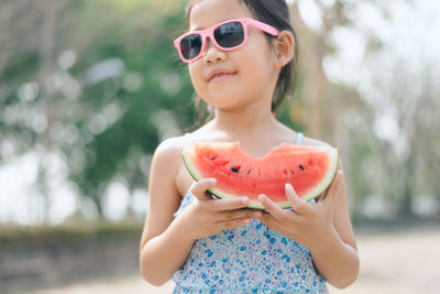 Close-up of smiling girl wearing sunglasses holding watermelon slice
