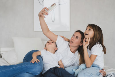 Side view of family sitting on bed at home