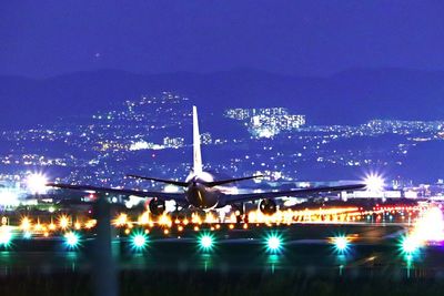 Illuminated airplane flying in sky at night