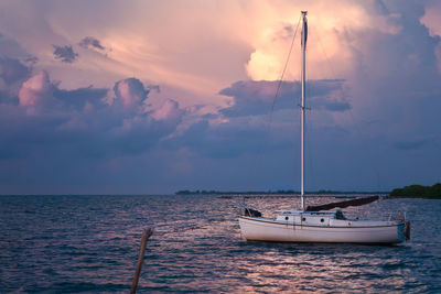 Sailboat sailing on sea against sky during sunset