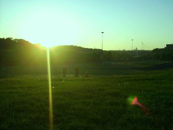 Scenic view of grassy field against sky at sunset