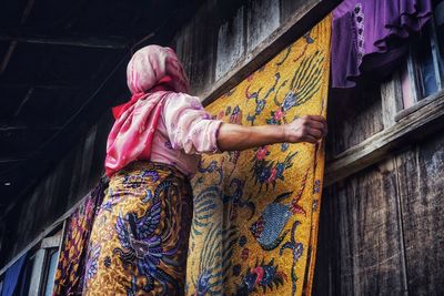 Side view of woman standing against multi colored wall