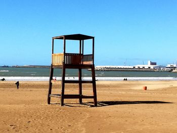 Lifeguard hut on beach against clear blue sky