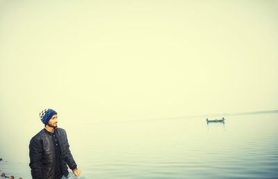 Man standing in sea against clear sky