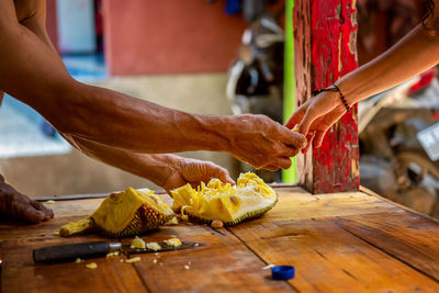 Photo of hands of balinese man cut exotic fruit durian in his house and share with tourist. bali 