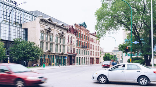 Cars on street in city against clear sky