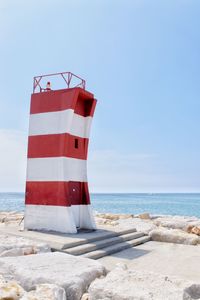 Red flag on rock at beach against sky