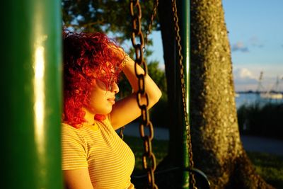 Portrait of young woman lying down on tree trunk