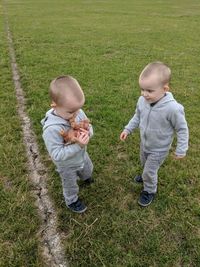 Full length of twin brothers standing on field