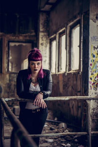 Portrait of woman standing by railing in abandoned building