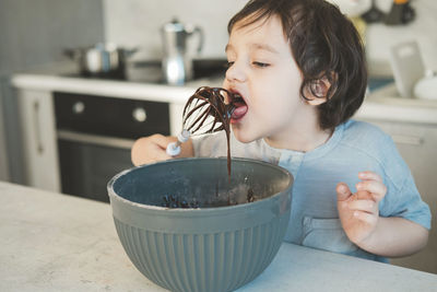 Boy licking chocolate in kitchen