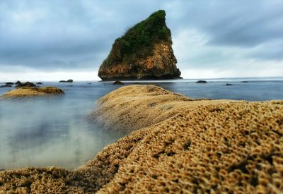 Rock formation on beach against sky