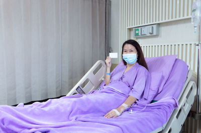 Rear view of woman sitting on bed at home