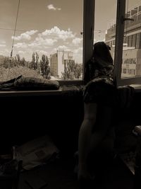 Rear view of man sitting by window in city