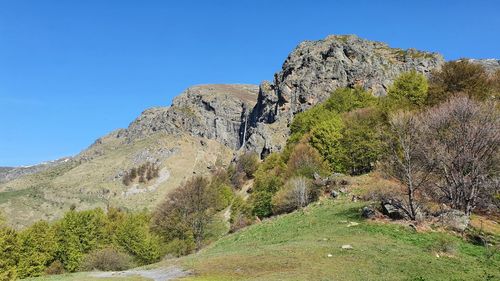 Low angle view of rocky mountain against clear blue sky