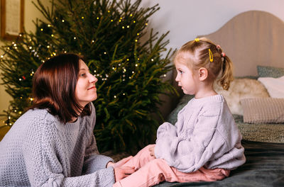 Portrait of young woman standing against christmas tree