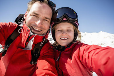 Portrait of cheerful father and daughter in warm clothing