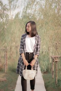 Young woman standing against trees
