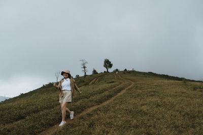 Woman walking on field against sky