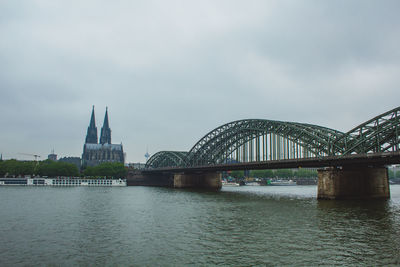 Arch bridge over river against cloudy sky