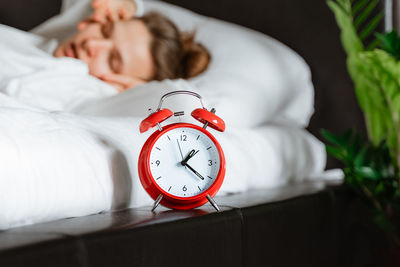 Sleepy  woman yawning rubbing eyes turning off red alarm clock in bedroom. day healthy sleep. 