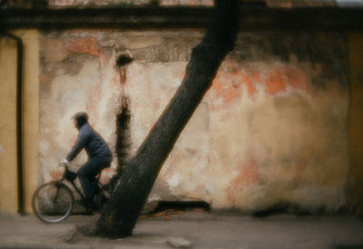Side view of man riding bicycle against wall