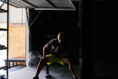 Young man working out with dumbells in a garage